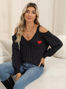 Detail of chunky knit sweater showing red heart embroidery on black shoulder cut-out