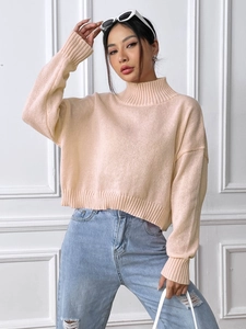 Close-up of peach mock neck knit sweater with ribbed cuffs and soft texture