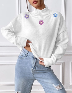 Detail of colorful embroidered flowers on white high neck knitted sweater collar