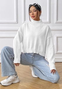Detail of white high-neck ribbed knit sweater paired with casual light blue ripped jeans