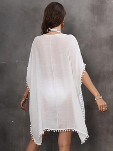 Detailed view of white beach cover-up with delicate pom-pom trim and back V-neck ties