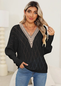 Detail of black crochet sweater featuring hollow knit texture and beige lace V-neckline trim