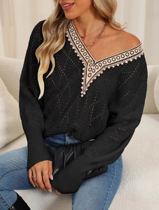 Detailed close-up of V-neck knitted sweater with delicate beige lace trim on black fabric