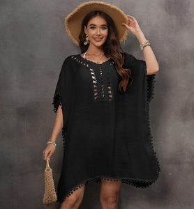 Detail of crochet neckline and pom-pom fringe trim on a black beach cover-up dress