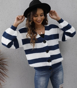 Dettaglio del cardigan in maglia a righe blu e bianche con bottoni grandi e scollo a V