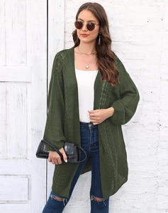 Detail of dark green knit cardigan featuring cable stitch texture and hollow-out pattern