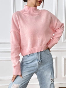 Detail of soft pink high-neck knit sweater featuring ribbed cuffs and drop shoulder texture