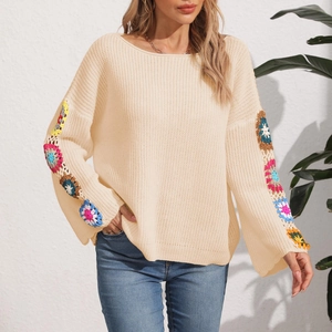 Close-up of beige knit sweater featuring colorful crochet floral patterns on sleeves