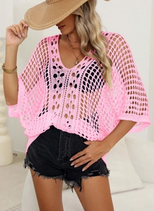 Close-up of pink crochet knit mesh fabric showing hollow out texture and loose batwing sleeves