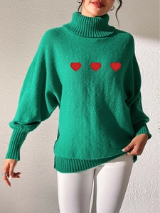Close-up of bright green turtle neck sweater with red heart embroidery and ribbed cuffs