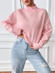 Detail of pink turtleneck knit sweater with drop shoulder and high waist ripped jeans