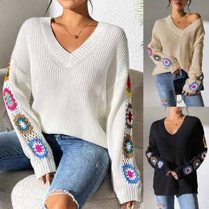 Detail of bohemian crochet flower patchwork sleeves on a V-neck knit sweater
