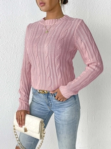 Detailed close-up of cable knit texture on a light pink long sleeve crew neck sweater