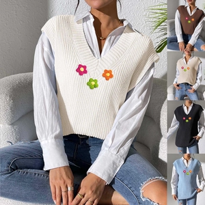 Détails de texture en tricot et broderie florale sur un gilet sans manches blanc à col en V