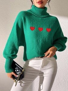 Detail of green turtleneck sweater with red heart patches and knitted texture