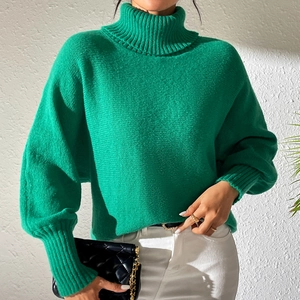 Detailed knit texture and high neck collar of the bright green minimalist women's sweater