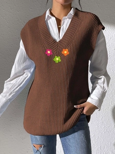 Détail du gilet en maille marron avec col en V, fleurs au crochet et texture épaisse