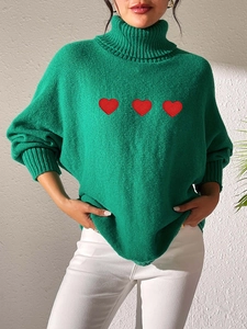 Detail of green high neck knit sweater featuring three red heart applique patches