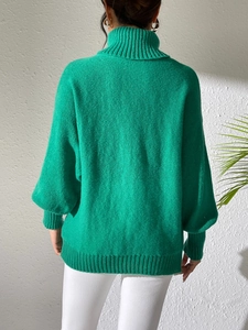 Rear view of a loose green turtleneck knitted sweater with dropped shoulders and ribbed cuffs