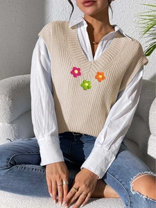 Texture de maille détaillée du gilet beige à col en V avec broderies florales 3D colorées