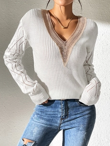 Detail of the V-neckline featuring delicate lace patchwork on a white knit sweater