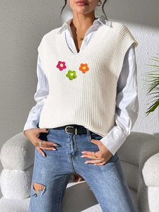 Détail du gilet en maille blanche à col en V avec des fleurs crochetées à la main en 3D