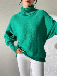 Detail of a bright green oversized turtleneck sweater with thick knit ribbed texture
