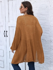 Detail of caramel knit cardigan showing long sleeves and intricate cable knit pattern texture