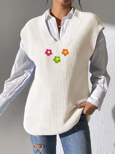 Détail du gilet en tricot blanc avec col en V et trois applications de fleurs au crochet