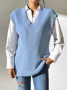 Detail of light blue V-neck knit vest with ribbed edges over a white long sleeve shirt