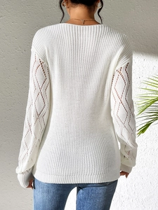 Detail of white knit sweater showing hollow diamond lace patterns on sleeves and back