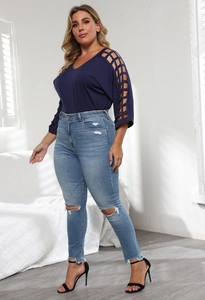 Detail of plus size top with hollow-out sleeves and distressed high-waist jeans