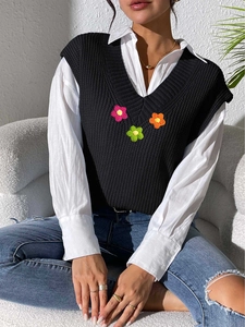 Détail de fleurs crochetées à la main sur un pull sans manches noir à col en V