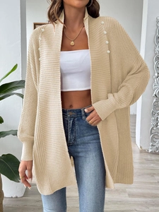 Close-up of oatmeal knit cardigan featuring elegant white pearl bead trim and soft texture