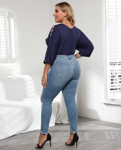 Detail of skinny jeans with knee cutouts and women's top with lace-up sleeve design