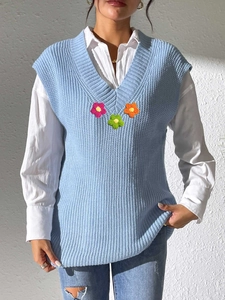 Détail de la maille du gilet bleu clair à col en V avec fleurs au crochet colorées