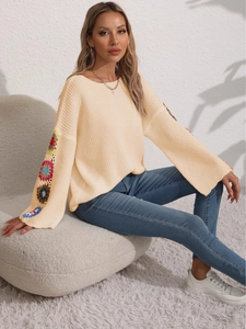 Beige oversized knit sweater featuring colorful crochet flower patches on long sleeves