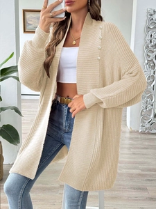 Detail of beige knit cardigan featuring chunky rib texture and elegant pearl embellishments