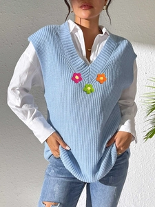 Gros plan détaillé du débardeur en tricot bleu clair avec fleurs au crochet 3D colorées