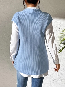 Rear view of light blue knitted vest paired with a white long-sleeve shirt and denim jeans