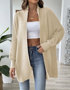 Detail of loose beige knitted cardigan showing ribbed cuffs and soft fabric texture