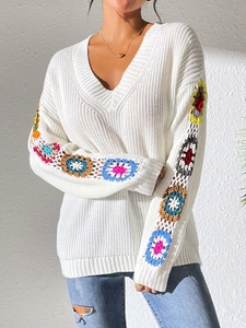 Detail of colorful hand-crocheted floral sleeve patchwork on a white V-neck sweater