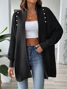 Close-up of black knit cardigan featuring elegant white faux pearl beads on the shoulder