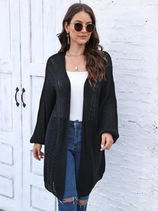 Detail shot of black knitted cardigan showing the intricate cable knit pattern and texture