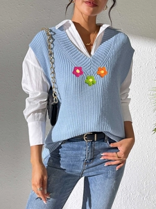 Détail du gilet en tricot bleu clair à col en V avec patchs floraux colorés faits main