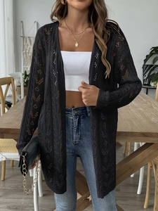Detail of black open-knit long cardigan featuring intricate hollow floral crochet patterns