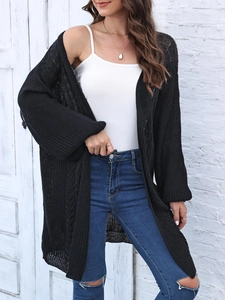 Outdoor shot of a black loose knit long cardigan featuring a textured openwork design