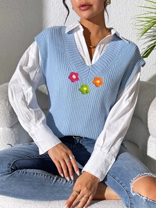 Détail du débardeur en maille bleu clair à col V avec appliques de fleurs au crochet