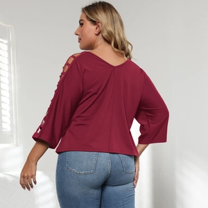 Detailed view of women's burgundy V-neck top featuring unique ladder cut-out sleeves