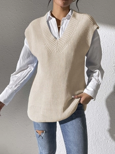 Detail of beige V-neck cable knit vest showing thick texture and ribbed edges on model